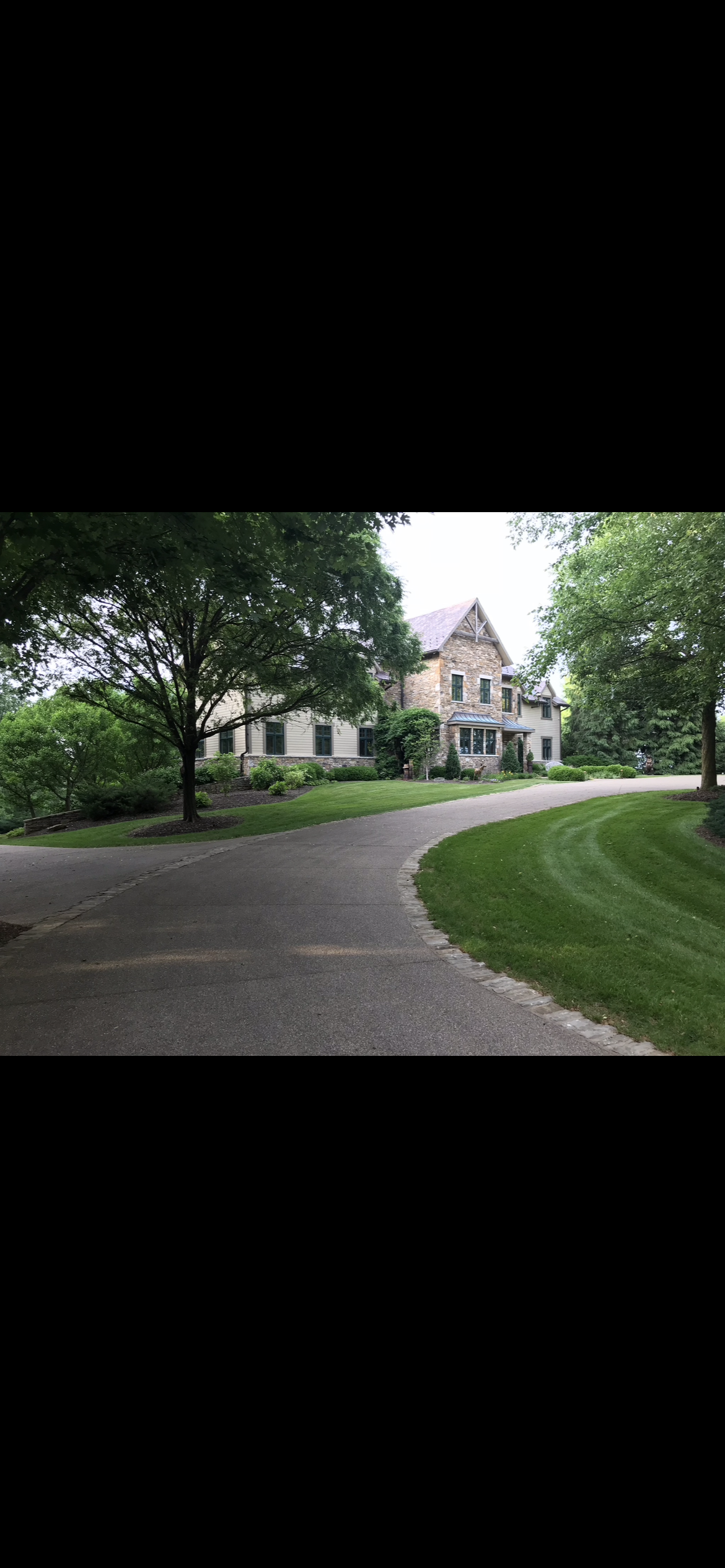Curved driveway approach with mature landscaping