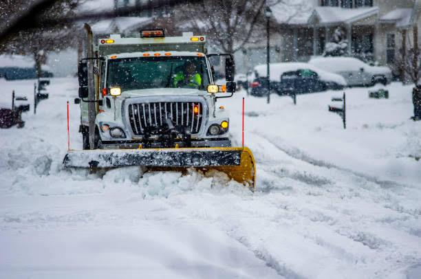 Professional snow plow clearing a residential street during a winter storm